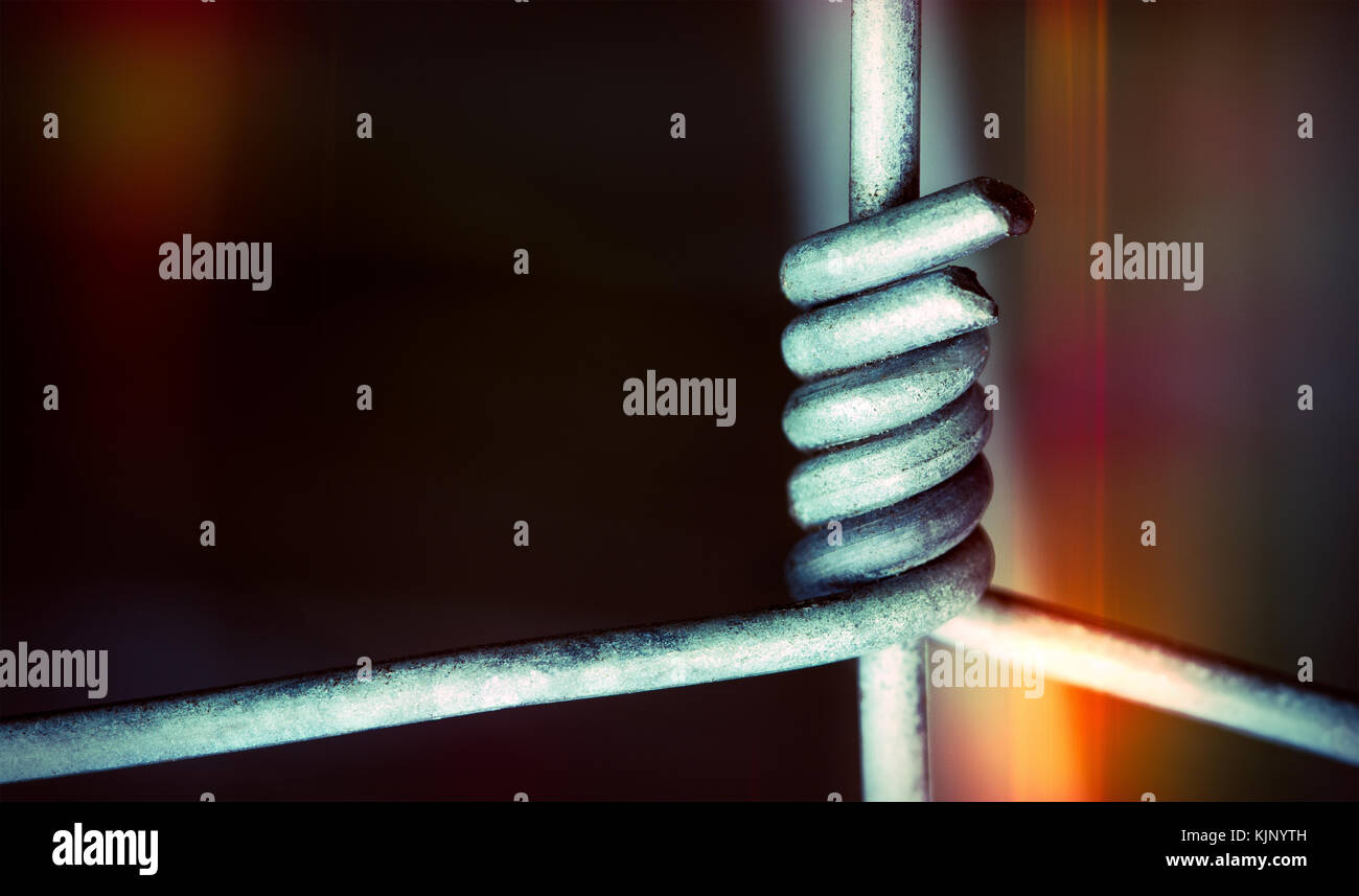 Fili metallici in stretto collegamento scuro su sfondo colorato. close-up di recinzione come concetto di aggancio, cooperazione, coesione o alleanza. Foto Stock