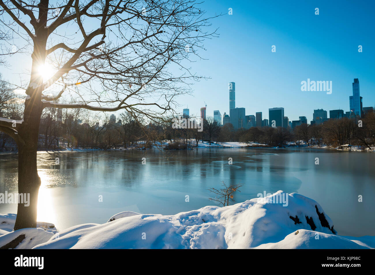 Vista panoramica dello skyline di manhattan riflettendo nel ghiaccio della congelata di central park Lake la mattina dopo un inverno tempesta di neve in new york city Foto Stock