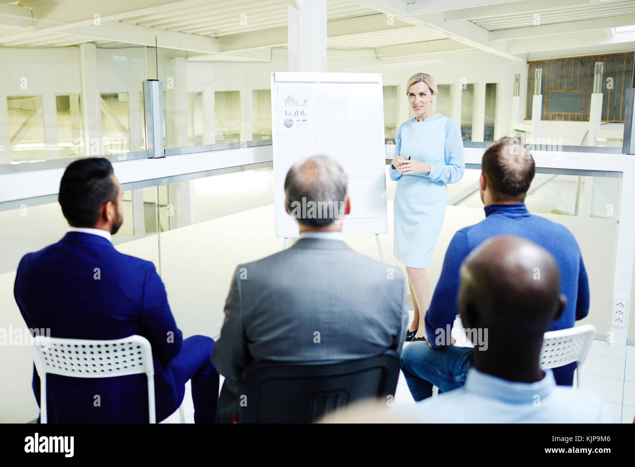 Fiducioso esperto finanziario in piedi dalla lavagna e parlare al pubblico durante la conferenza Foto Stock