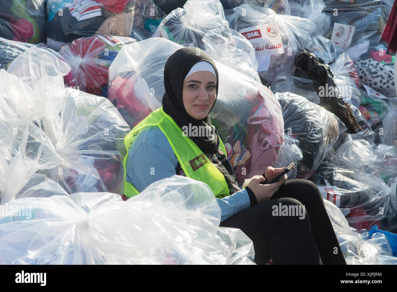 Marytrs' Square, Beirut, Libano, 26 Nov 2017, musulmano volontari femmina sedeva accanto a sacchetti di vestiti per le donazioni tramite telefono cellulare Beirut, Libano, Credito: Mohamad Itani / Alamy Live News Foto Stock