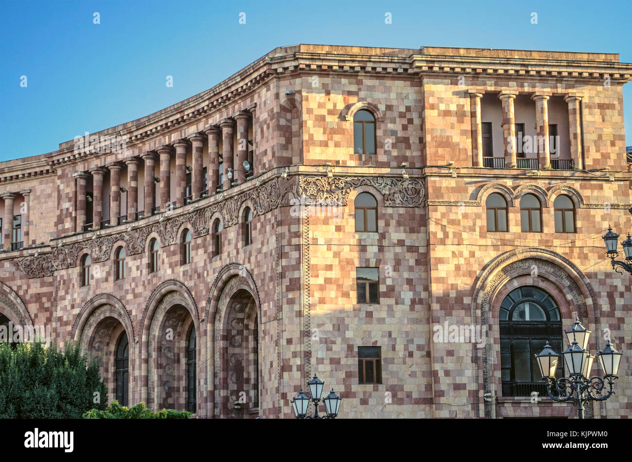 Edificio amministrativo di motley pietra con un bassorilievo di arredamento etnico sulla piazza centrale in Yerevan capitale dell'armenia Foto Stock