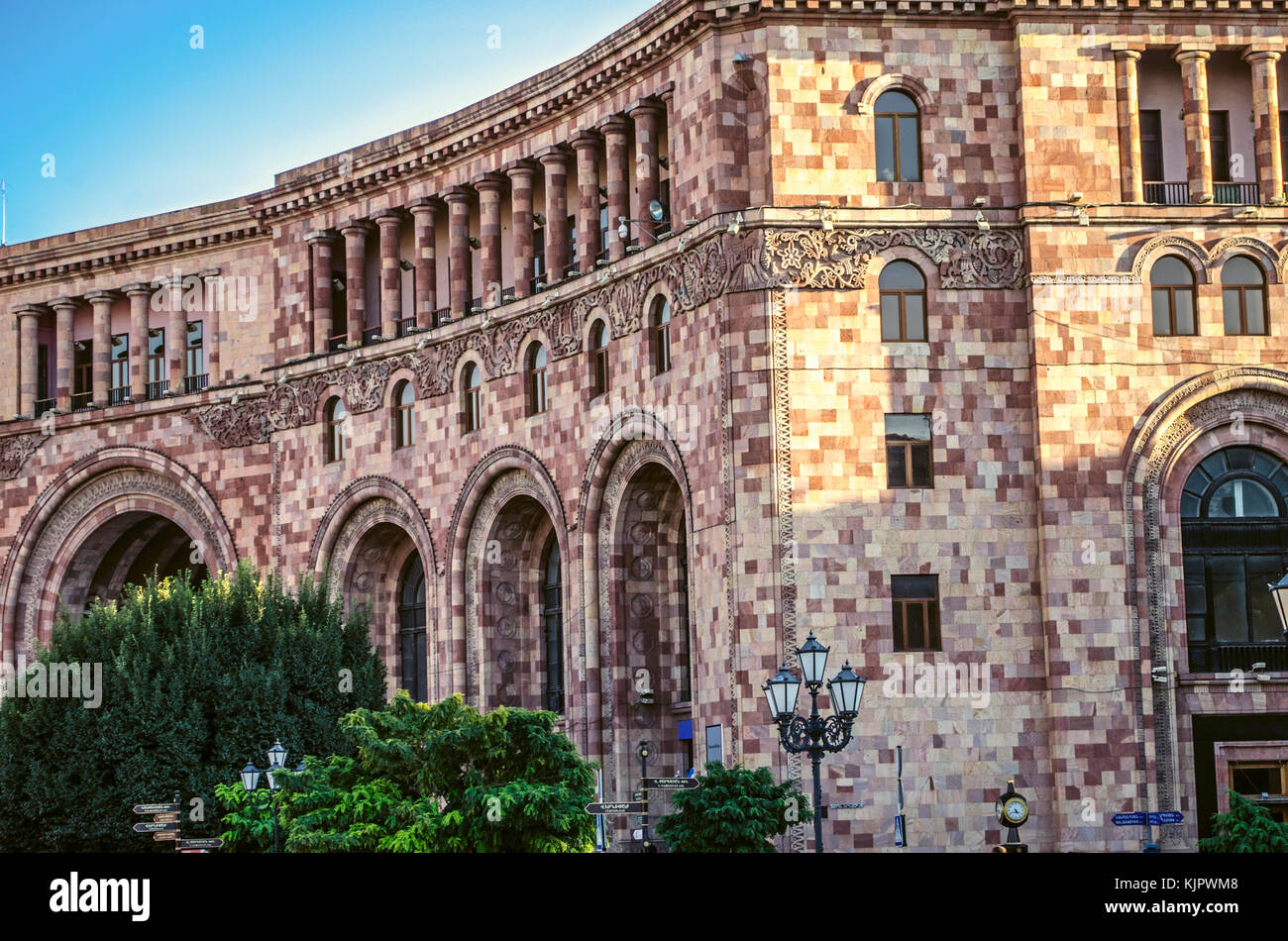 Edificio amministrativo di motley pietra con un bassorilievo di arredamento etnico sulla piazza centrale di Yerevan Foto Stock