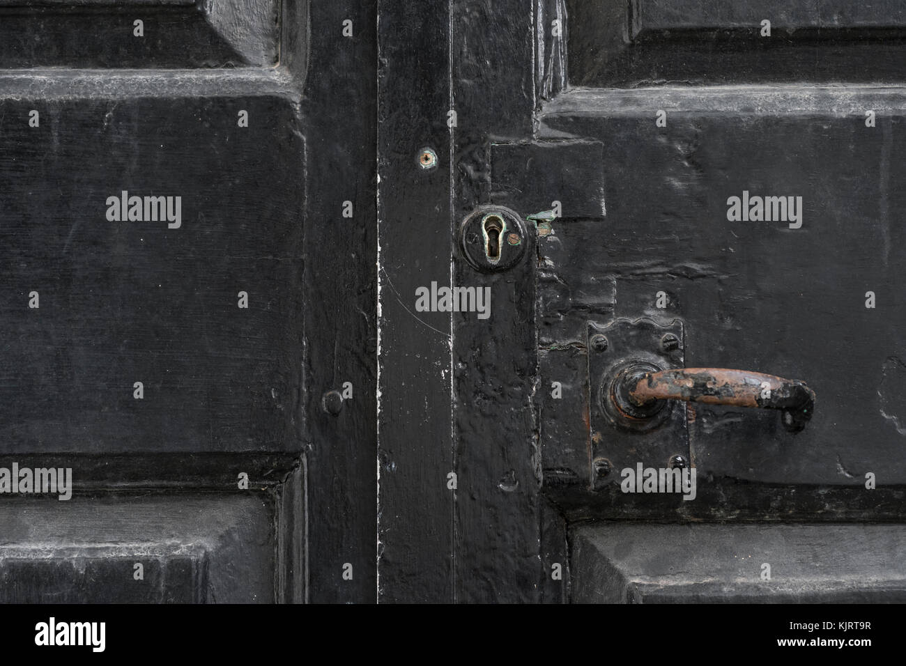 Vecchio nero esterno porte dipinte con indossato keyhole e maniglia. Bloccato in posizione e bloccare in posizione la metafora. Foto Stock