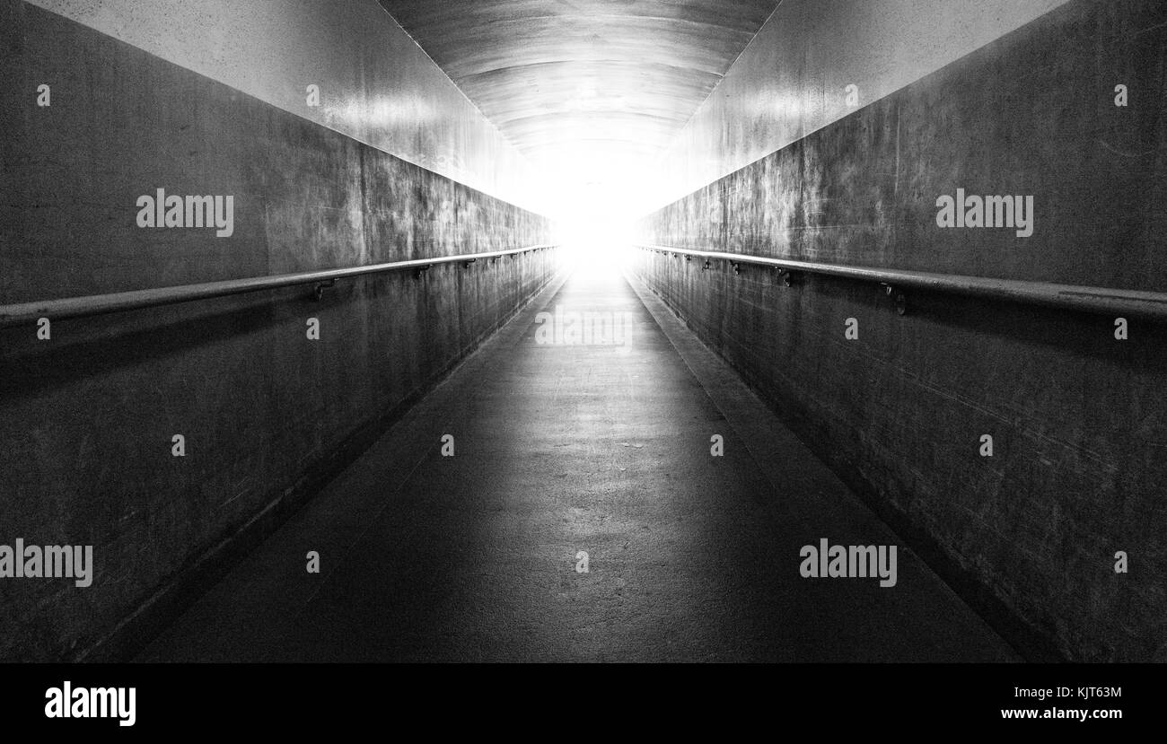 Un lungo corridoio sotterraneo conduce la superficie e la luce alla fine del tunnel Foto Stock