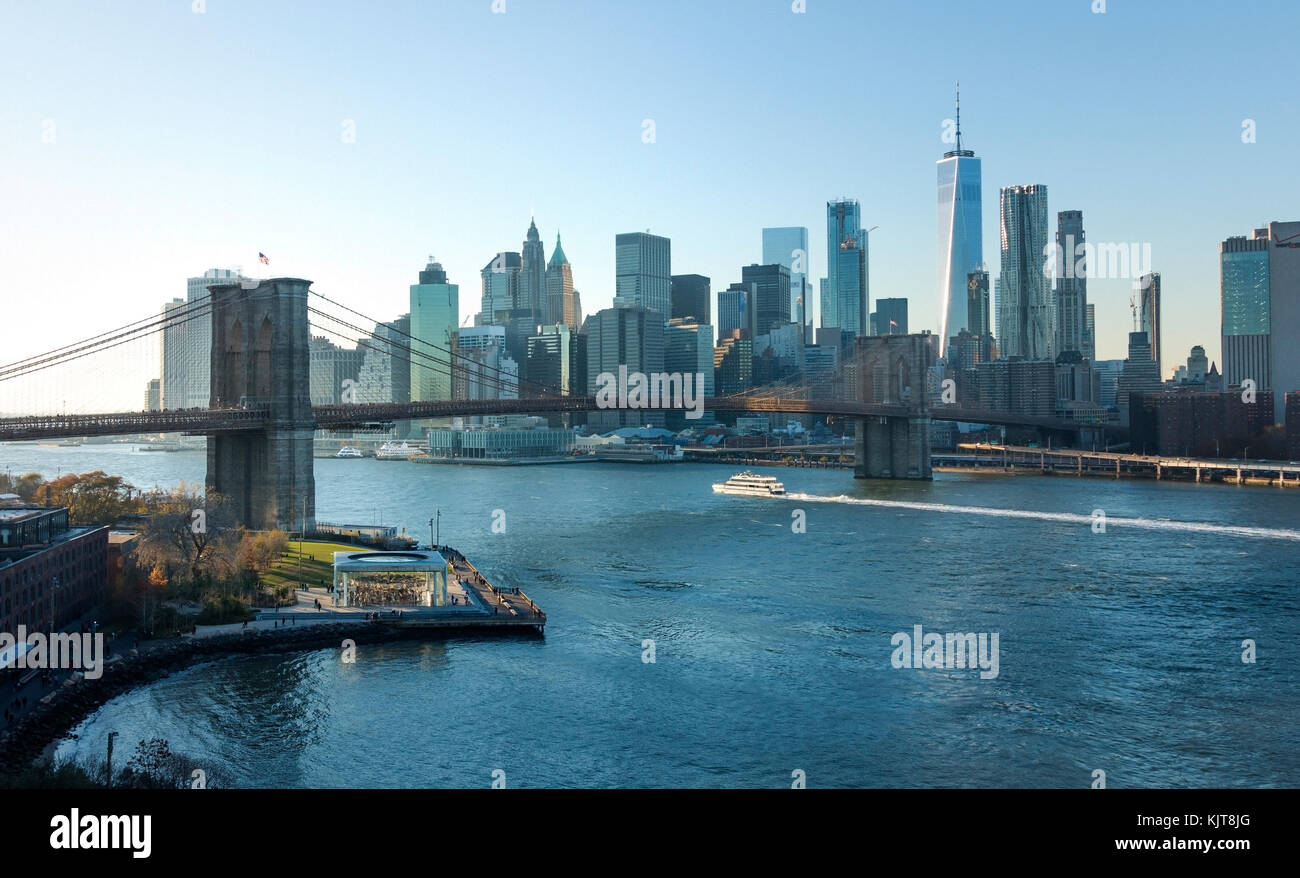 East River Ferry passando sotto il ponte di Brooklyn con la parte inferiore della skyline di Manhattan in background Foto Stock