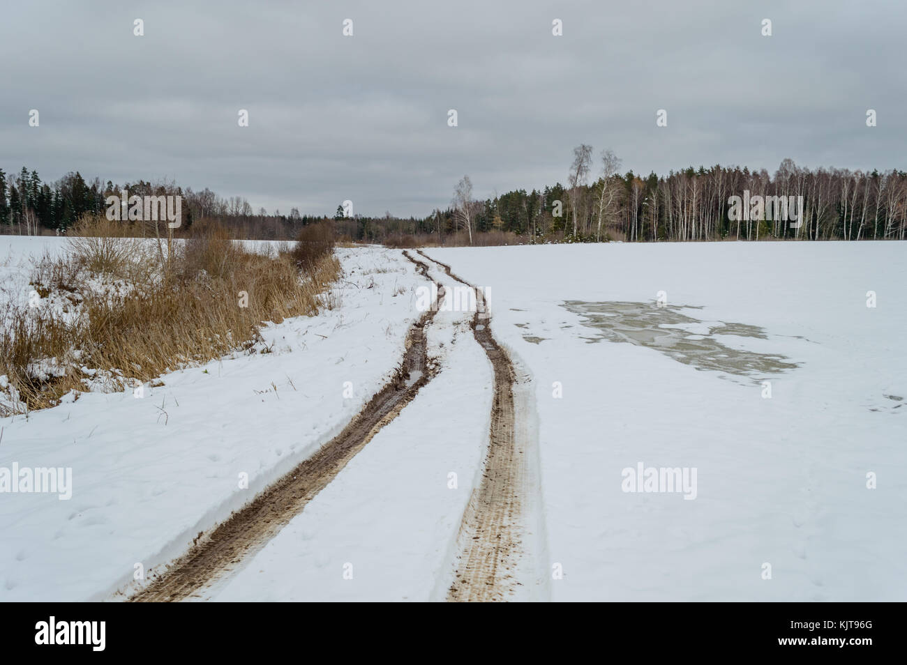 Paese strada in inverno con tracce di pneumatici nella neve e nel ghiaccio Foto Stock