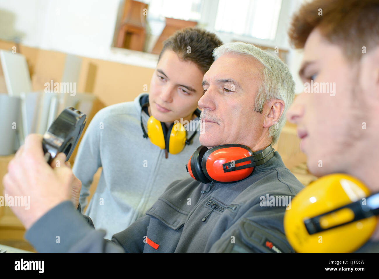 Uomo con apprendisti tenendo il cuscinetto Foto Stock