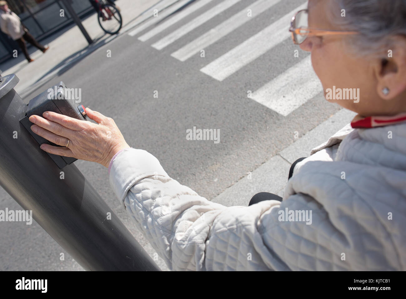 Donna anziana premendo il pulsante crosswalk Foto Stock