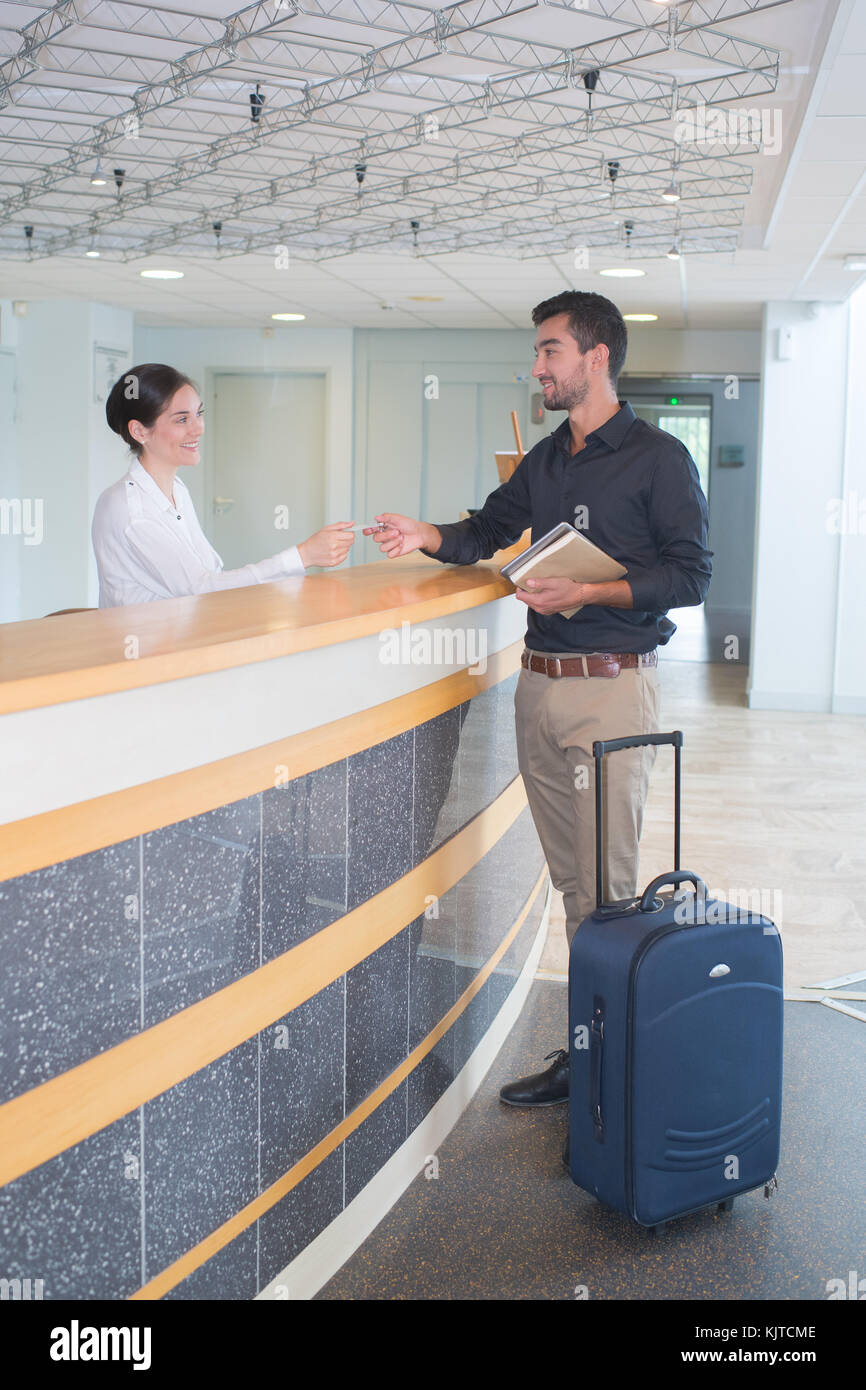 Imprenditore esegue il controllo e la receptionist paga con carta di credito pagare Foto Stock