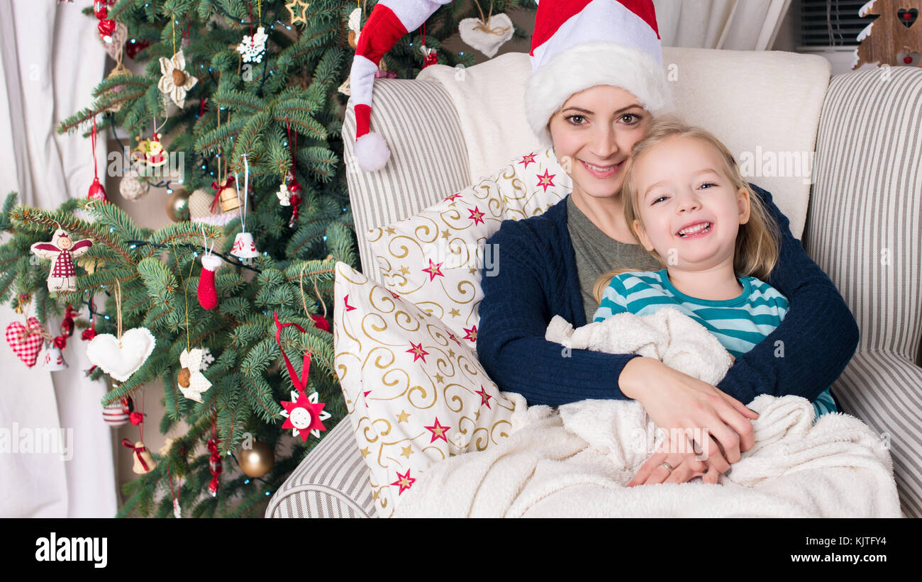 Autentica famiglia ritratto di natale nella parte anteriore del albero di natale. Sorridendo madre e figlia godendo di natale. Foto Stock