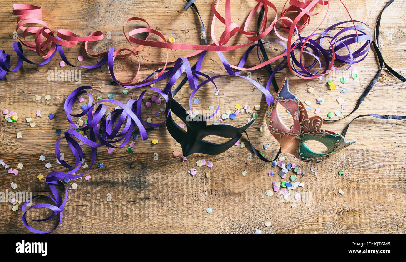 Festa di carnevale. maschere, coriandoli e serpentine su sfondo di legno, top niew, spazio di copia Foto Stock
