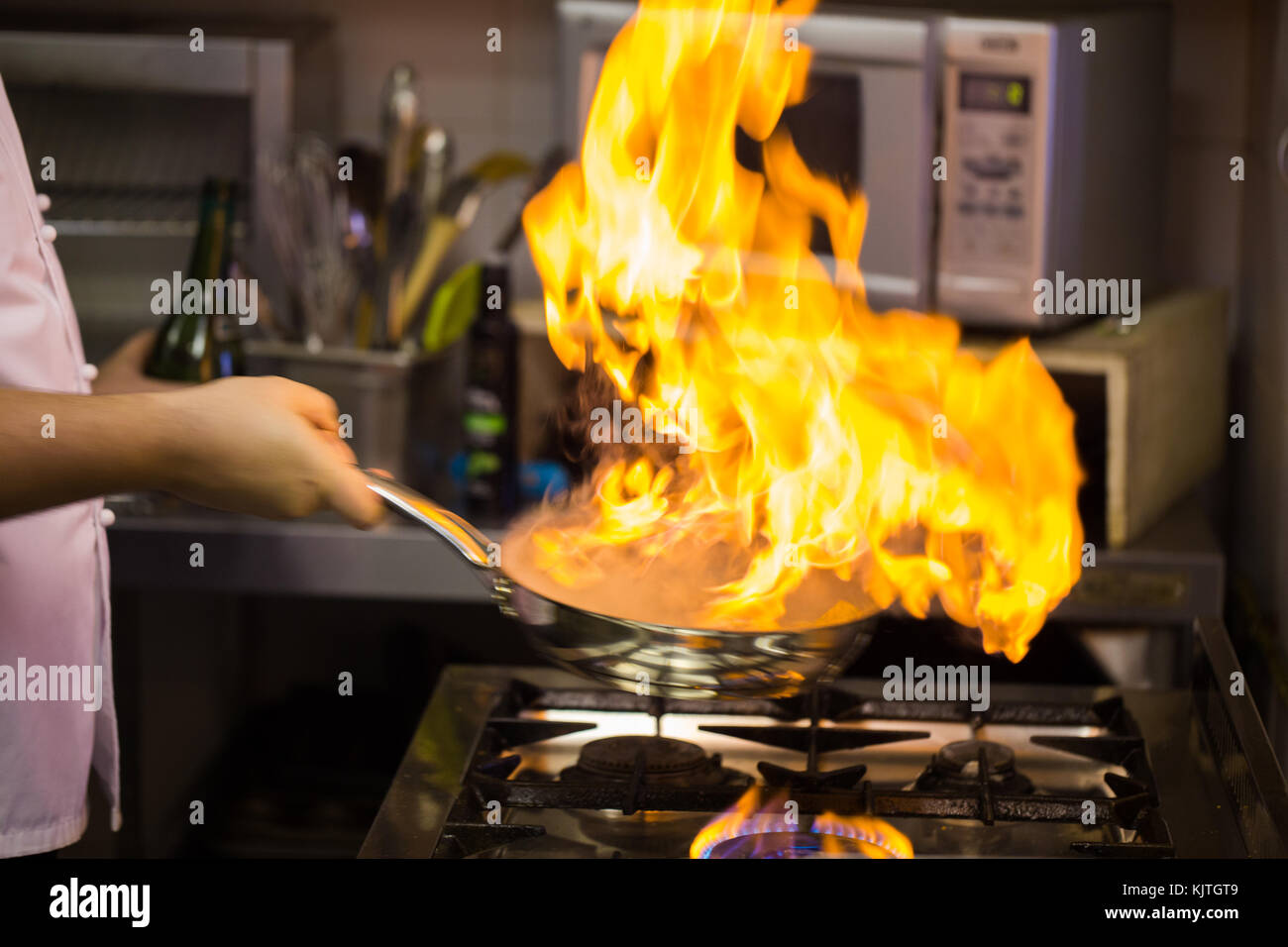 Lo chef cucinare il cibo in stile flambe su un fornello a gas. Luce  naturale e luce dalle fiamme Foto stock - Alamy