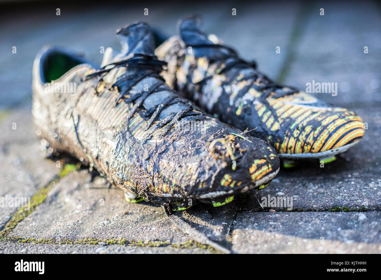 Un paio di scarpe da calcio junior molto ricoperte di fango Foto Stock
