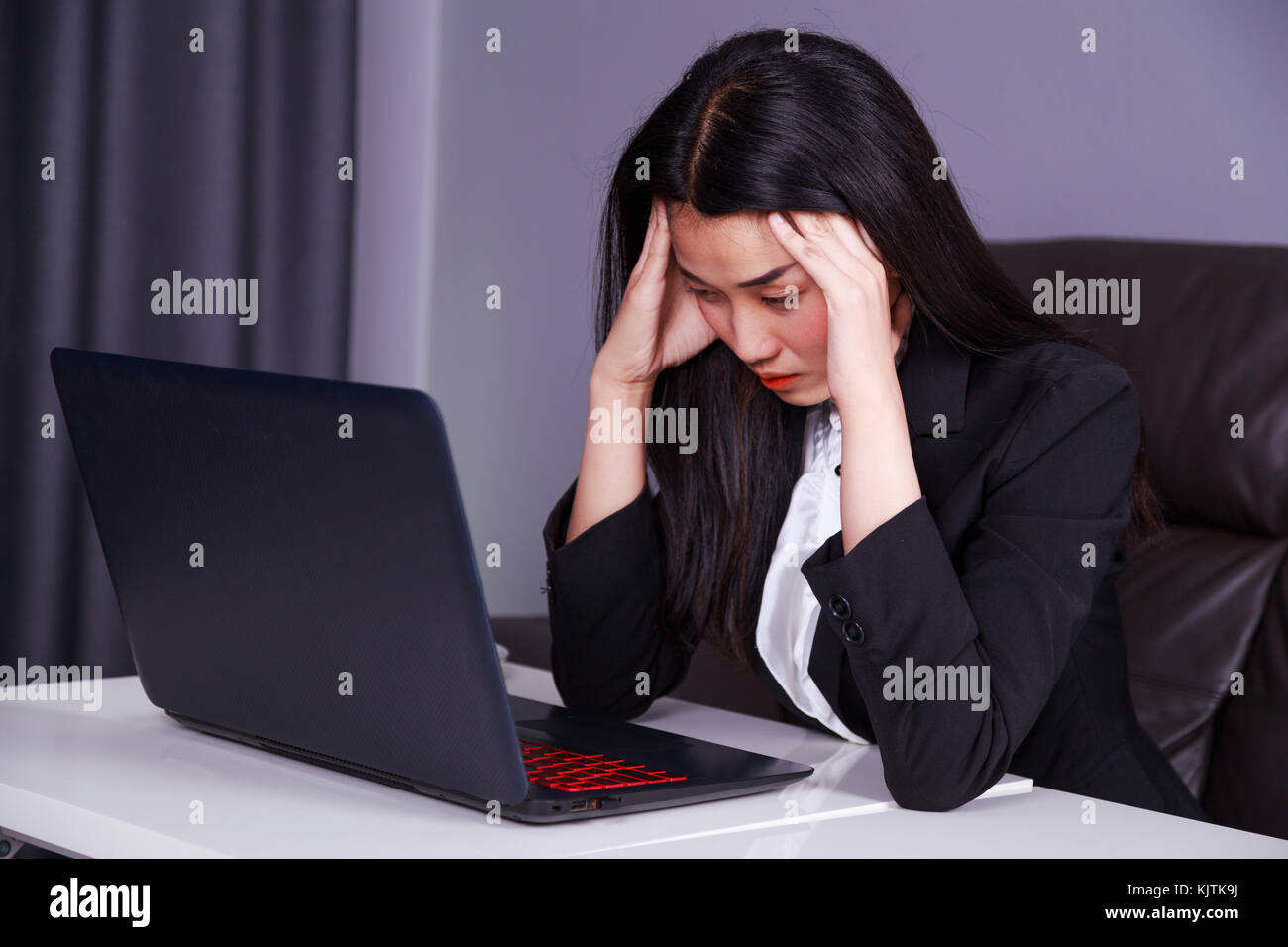 Giovane donna in business suit lavora con il computer portatile in disperata di stress Foto Stock