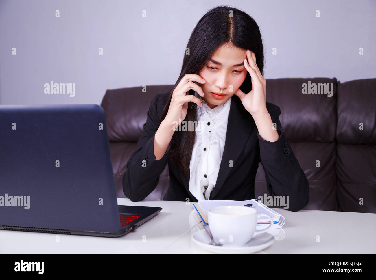 La donna nel business suit lavora nella sollecitazione disperati a parlare su un telefono mobile Foto Stock