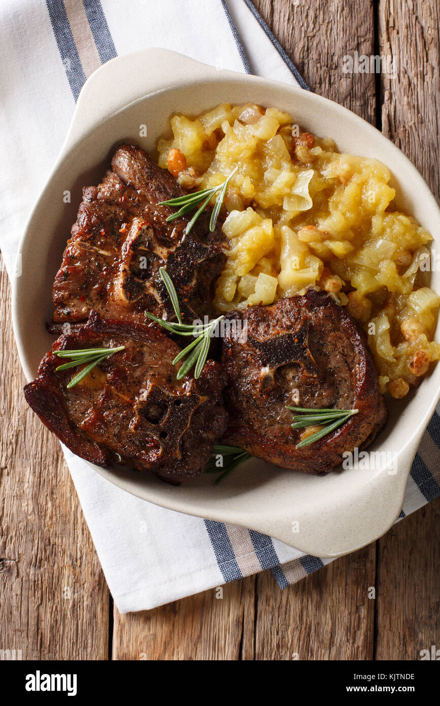 Agnello arrosto bistecca e mostarda di mele speziate close-up in una ciotola sul tavolo. verticale in alto vista da sopra Foto Stock
