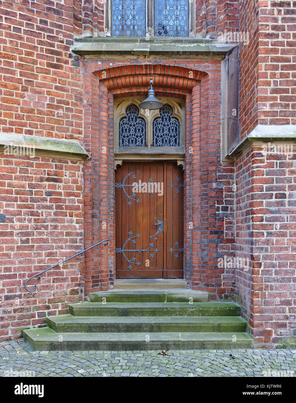 Vecchia porta di legno in un muro di mattoni con finiture in ferro, passaggi e ornati in Windows Foto Stock
