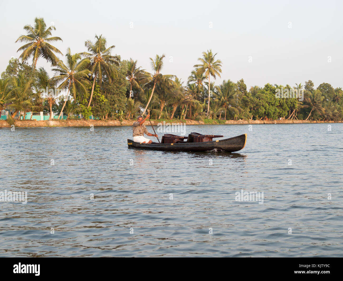 Un uomo attraversa nella sua canoa un ampio canale in Kerala backwaters Foto Stock