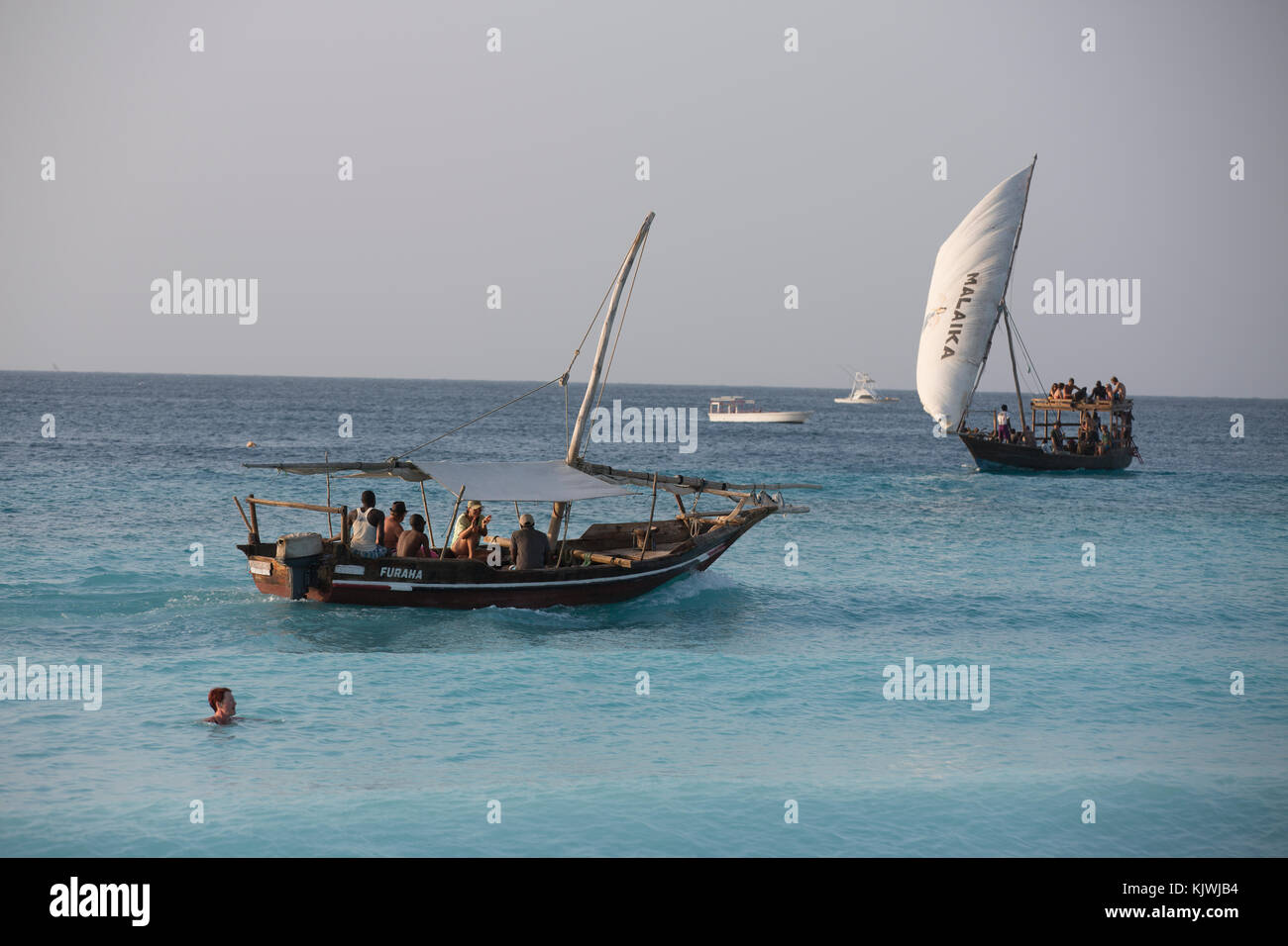 Zanzibar, Tanzania; imbarcazioni locali portano i turisti fuori su brevi viaggi per mare da alberghi a nord dell'isola. Foto Stock