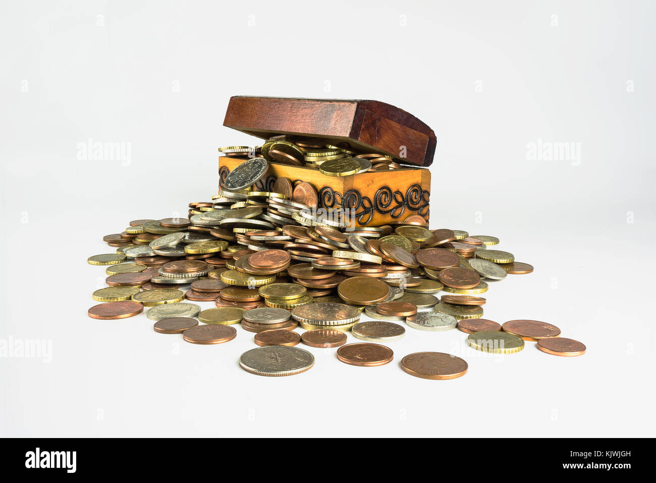 Un piccolo tesoro in legno petto che scoppia di monete su uno sfondo bianco. composizione isolata che è correlata alla sfera economica Foto Stock