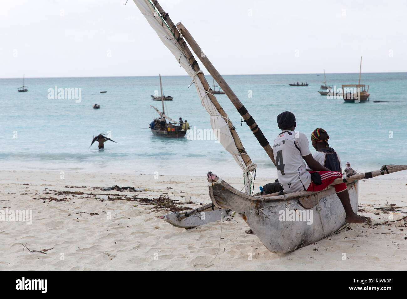 Nungwe, Zanzibar, Tanzania; donne pesce commercianti guardare come i pescatori portano le loro catture. Foto Stock