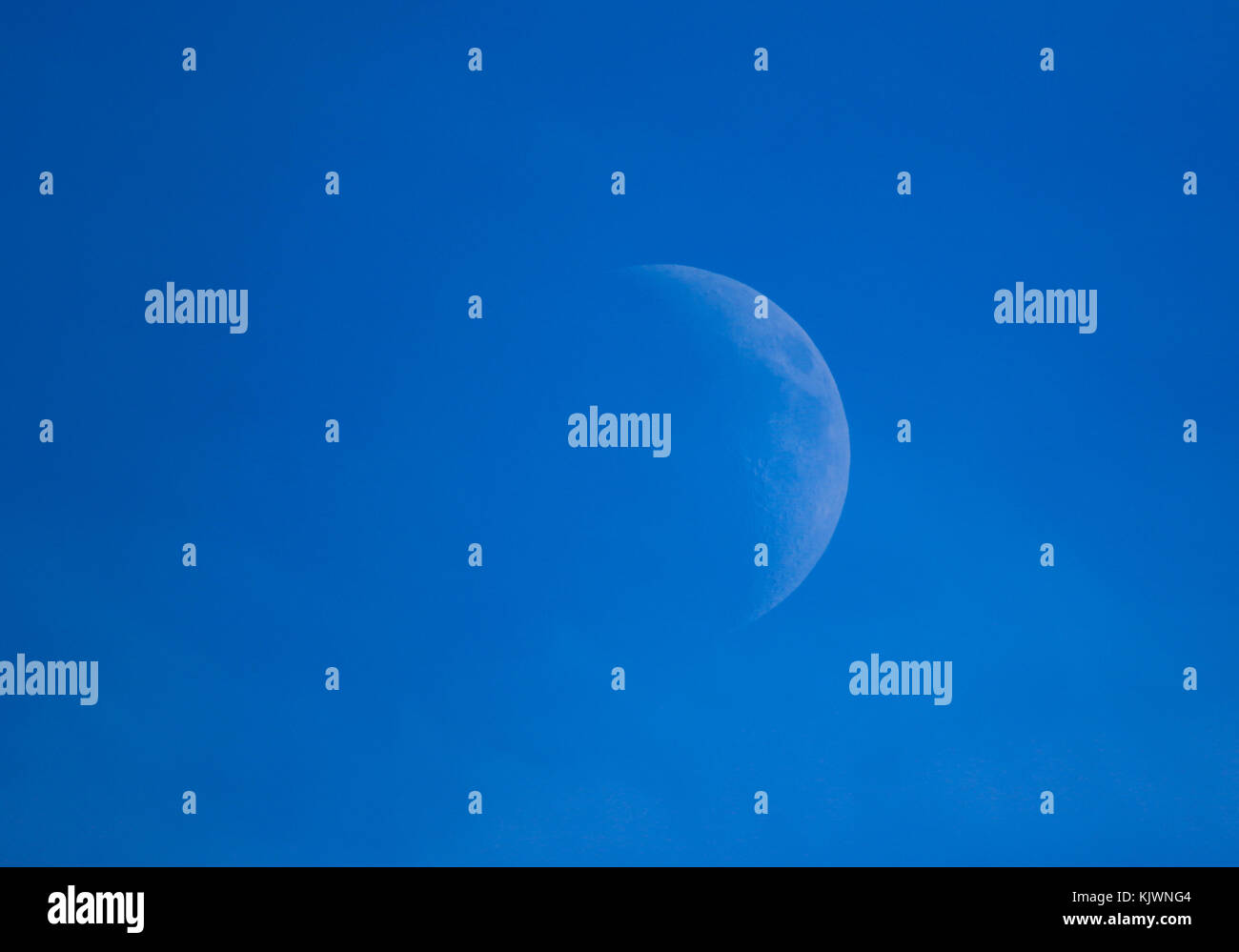 Mezza Luna appesa in un luminoso cielo blu Foto Stock