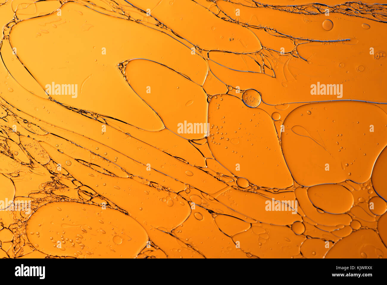 Modelli di olio in acqua contro una di oro o di sfondo arancione astratto macro Foto Stock