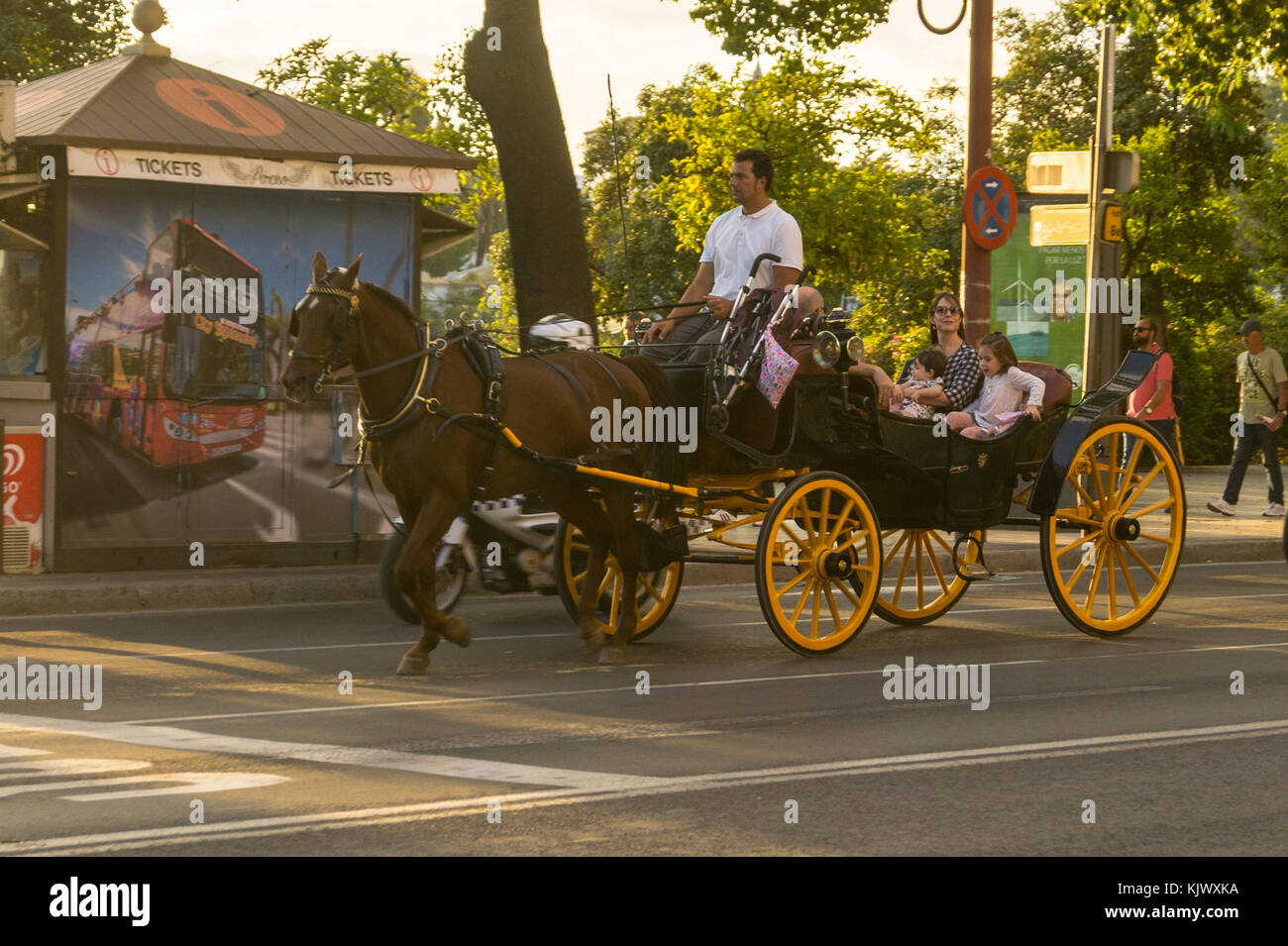 A cavallo il landau carrello con una donna sorridente e bambini come passeggeri, il fiume Guadalquivir waterfront, Siviglia, in Andalusia, Spagna Foto Stock