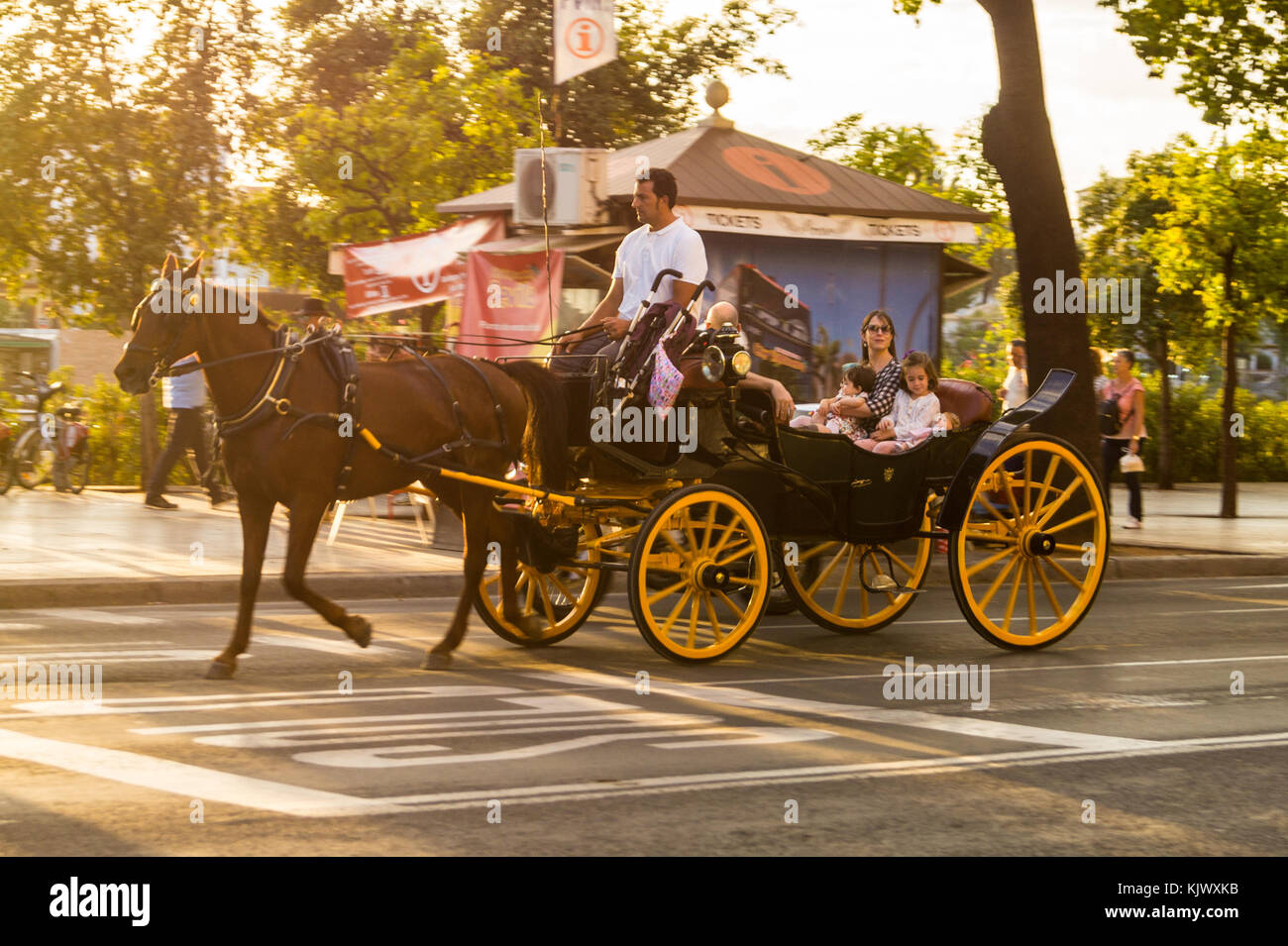 A cavallo il landau carrello con una donna sorridente e bambini come passeggeri, il fiume Guadalquivir waterfront, Siviglia, in Andalusia, Spagna Foto Stock