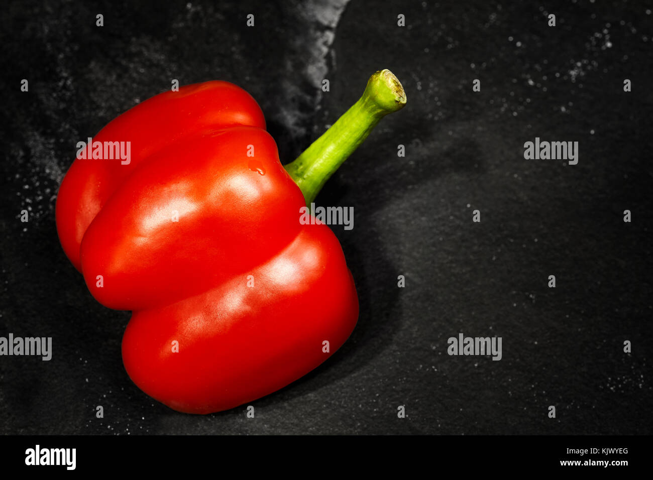 Tagliare a metà il peperone rosso al buio su un sfondo di ardesia, il fuoco selettivo, spazio per il testo. Foto Stock