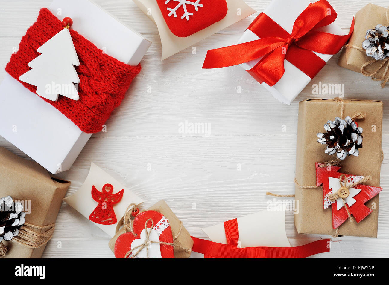Natale regalo Scatole decorate con archetti in rosso sono disposti in un cerchio su un bianco sullo sfondo di legno. flat laico, top view photo mockup Foto Stock