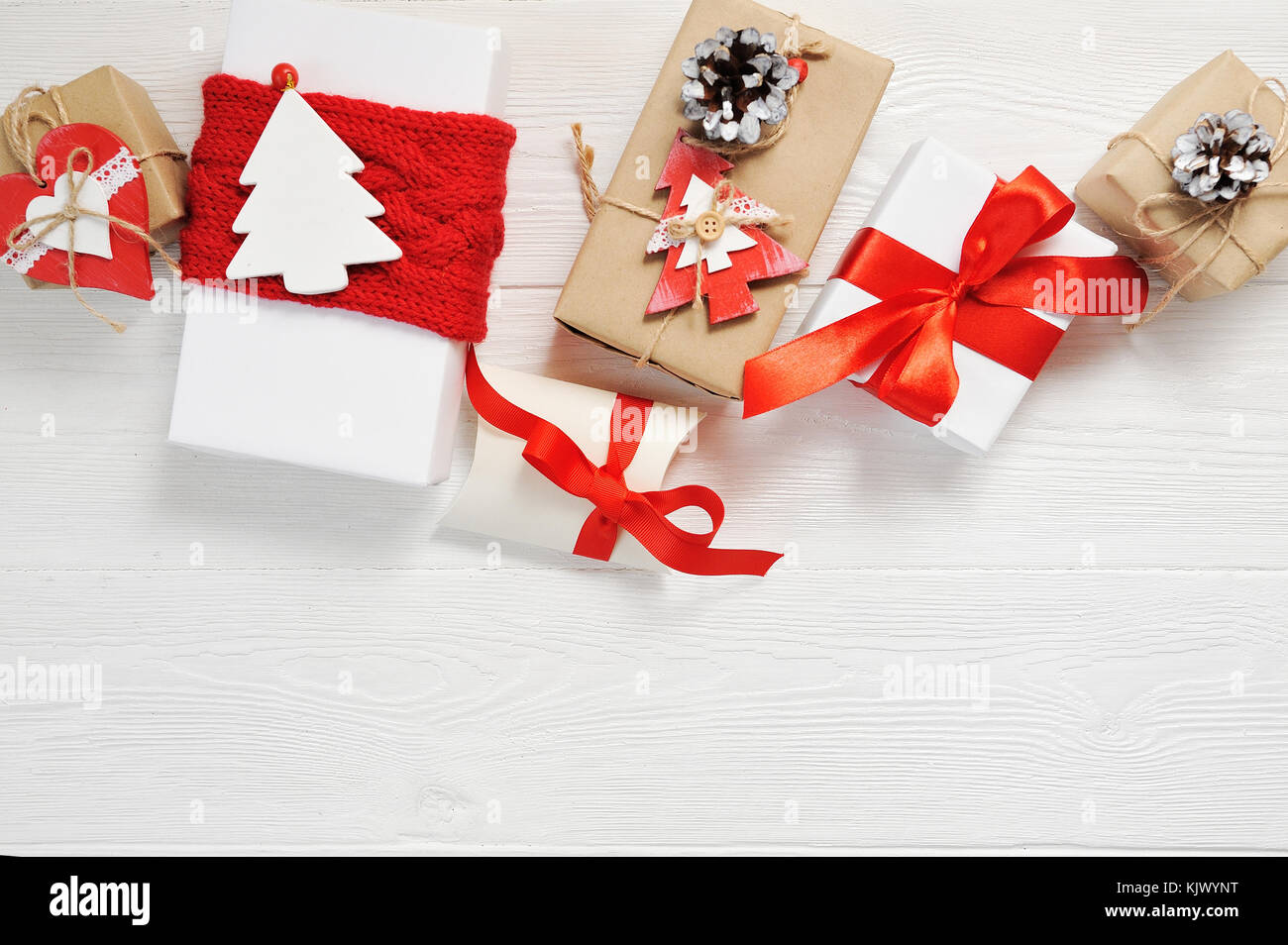 Natale regalo Scatole decorate con archetti in rosso su bianco sullo sfondo di legno. flat laico, top view photo mockup Foto Stock