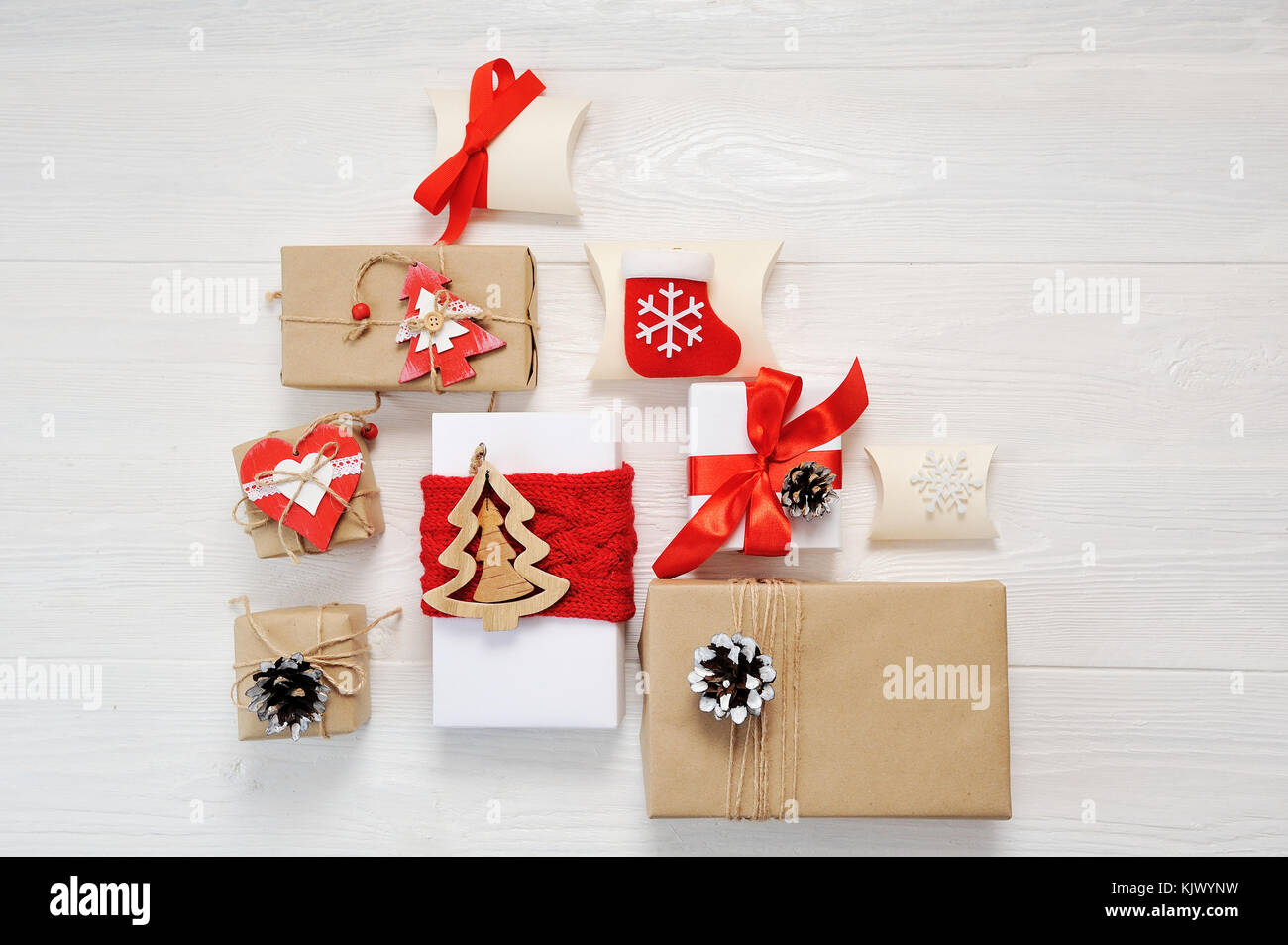 Mockup pacchi in carta avvolta legato con tag. un cuore rosso e qualche regalo di Natale scatole avvolto con della carta kraft e legato con il rosso e bianco bakers spago su un bianco tavolo in legno. in stile vintage Foto Stock