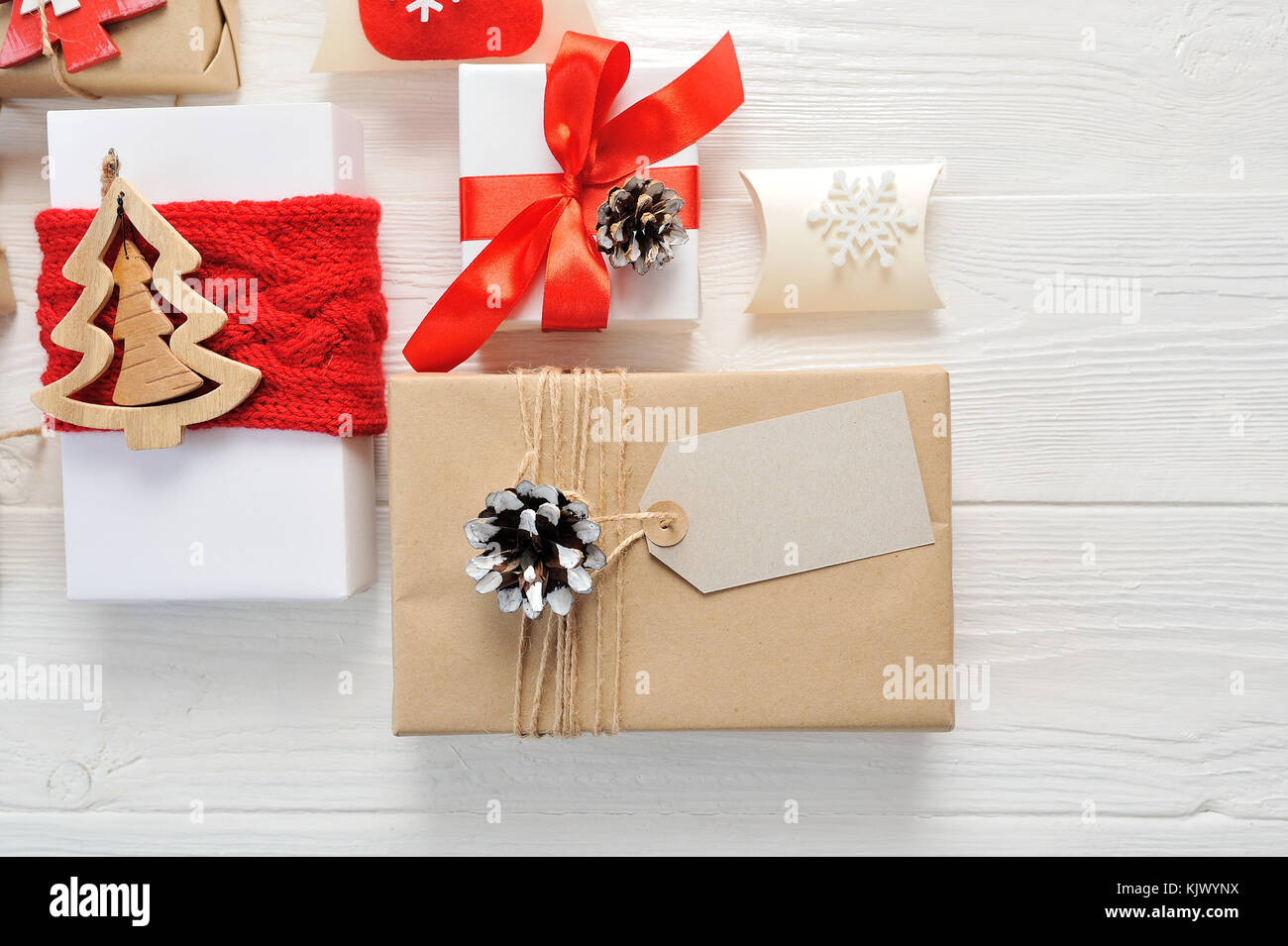 Mockup composizione di natale. regalo di Natale, tag coperta di maglia, pigne, Abete rami di legno su sfondo bianco. flat laico, vista dall'alto Foto Stock