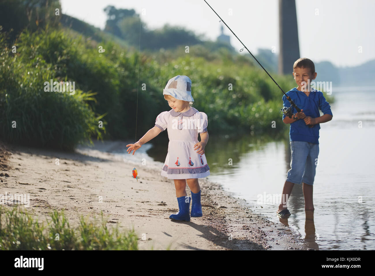 Un ragazzo e una ragazza con asta sulla costa del fiume Foto Stock