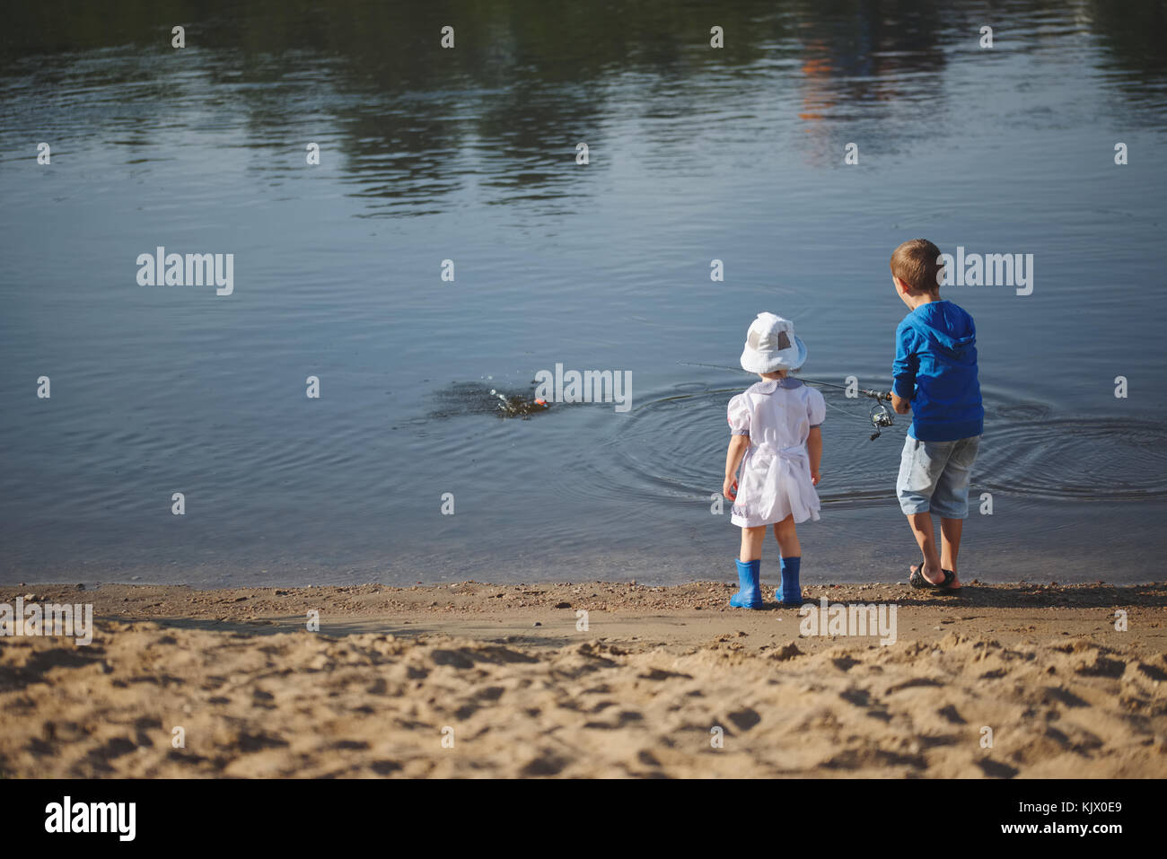 Un ragazzo e una ragazza con asta sulla costa del fiume Foto Stock