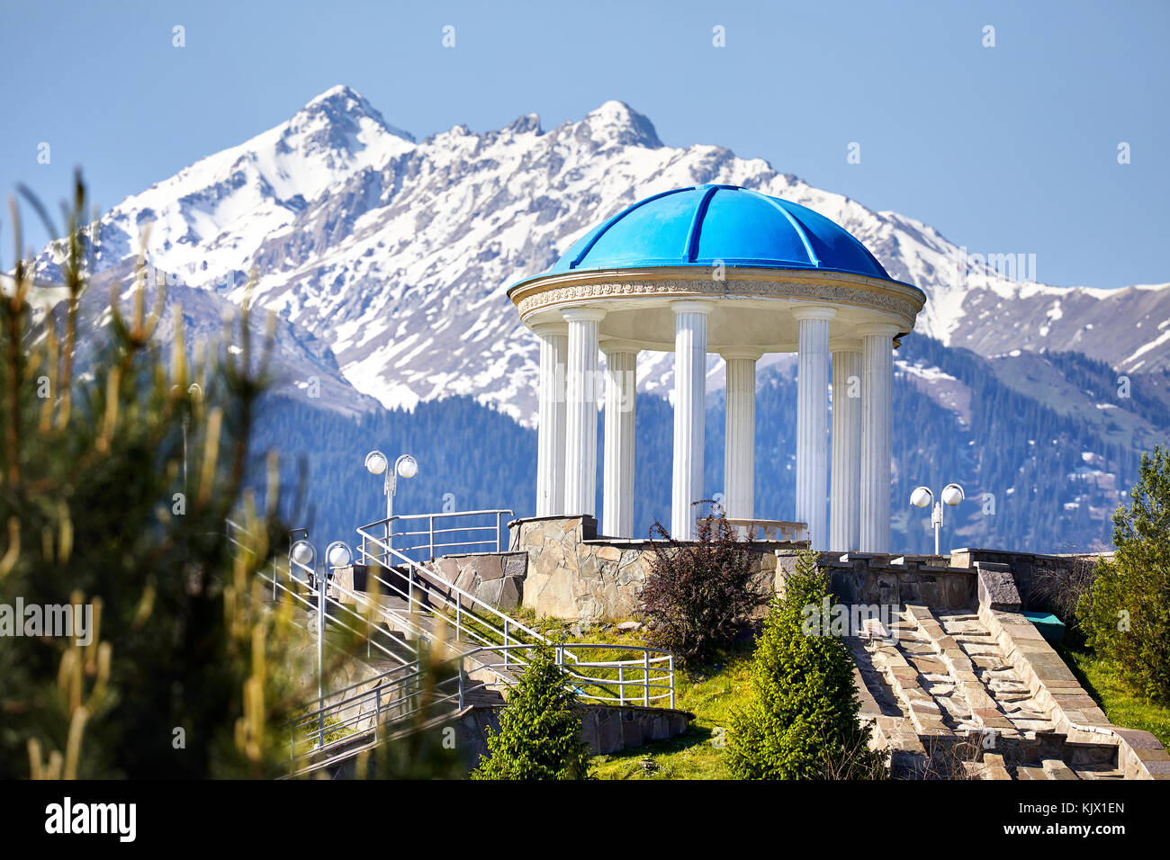 Monumento con colonna a montagne innevate sullo sfondo nel parco del primo n Almaty, Kazakhstan Foto Stock