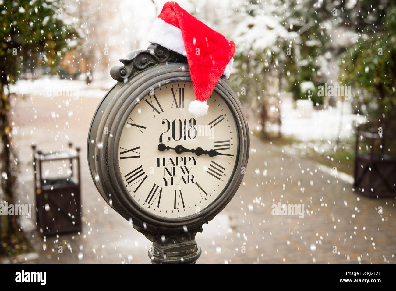 Orologio di strada vintage con il titolo Happy New Year 2018 e cappello di Babbo Natale su di loro con fiocchi di neve cadenti Foto Stock