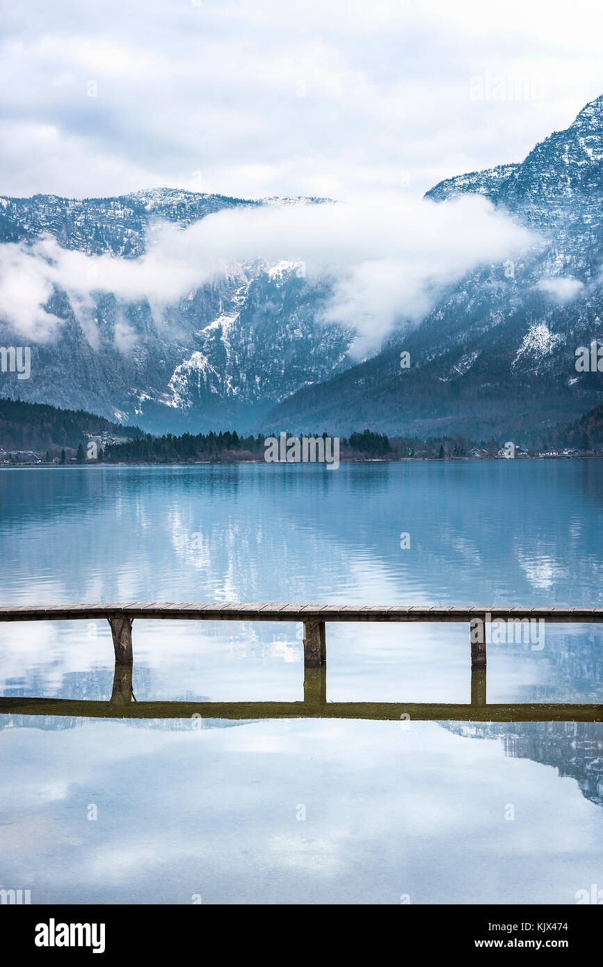 Percorsi di viaggio Tema immagine con le alpi austriache si riflette nel lago hallstatter e da un ponte che attraversa, situato in hallstatt, Austria Foto Stock