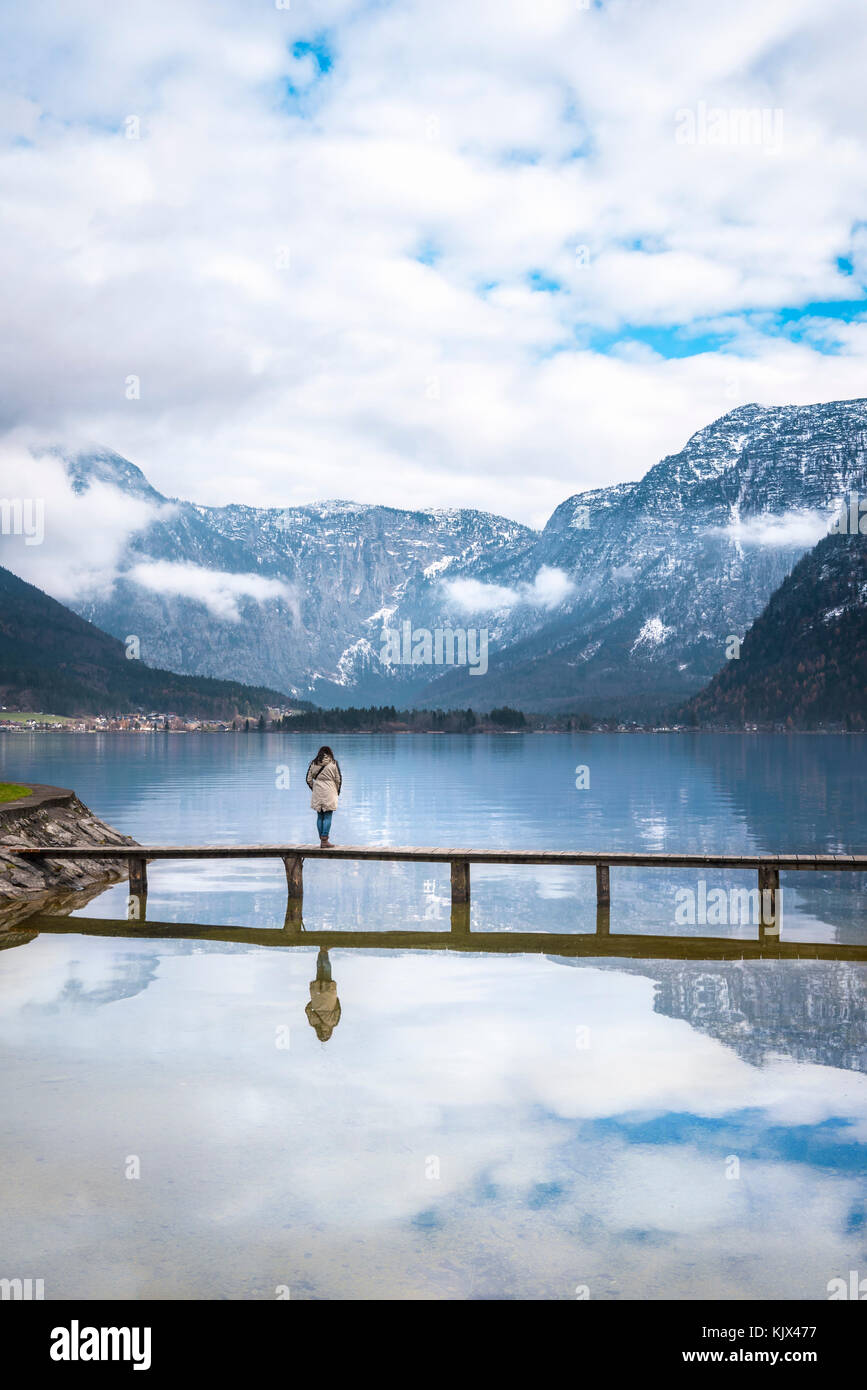 Momenti zen Tema immagine con una donna in piedi da solo su un ponte sopra il lago hallstatter, circondati dal silenzio e le montagne in Austria Foto Stock