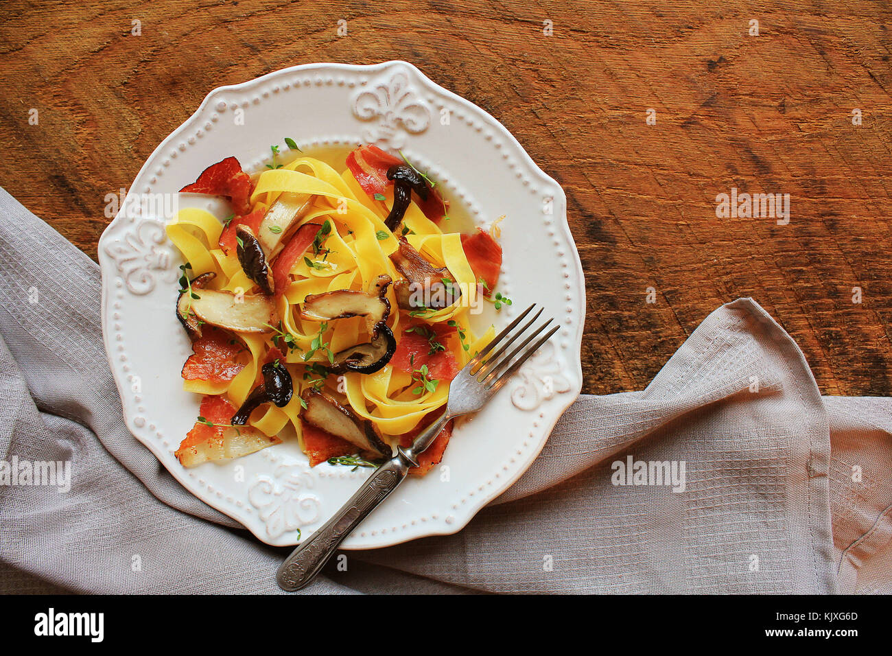 Tagliatelle con funghi commestibili e bacon in legno rustico bacground . Vista superiore Foto Stock