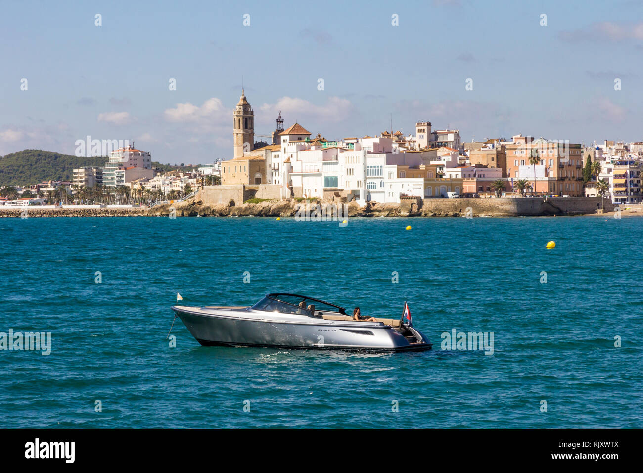 Power Boat ancorato con Sitjes città vecchia in background, Catalogna, Spagna Foto Stock