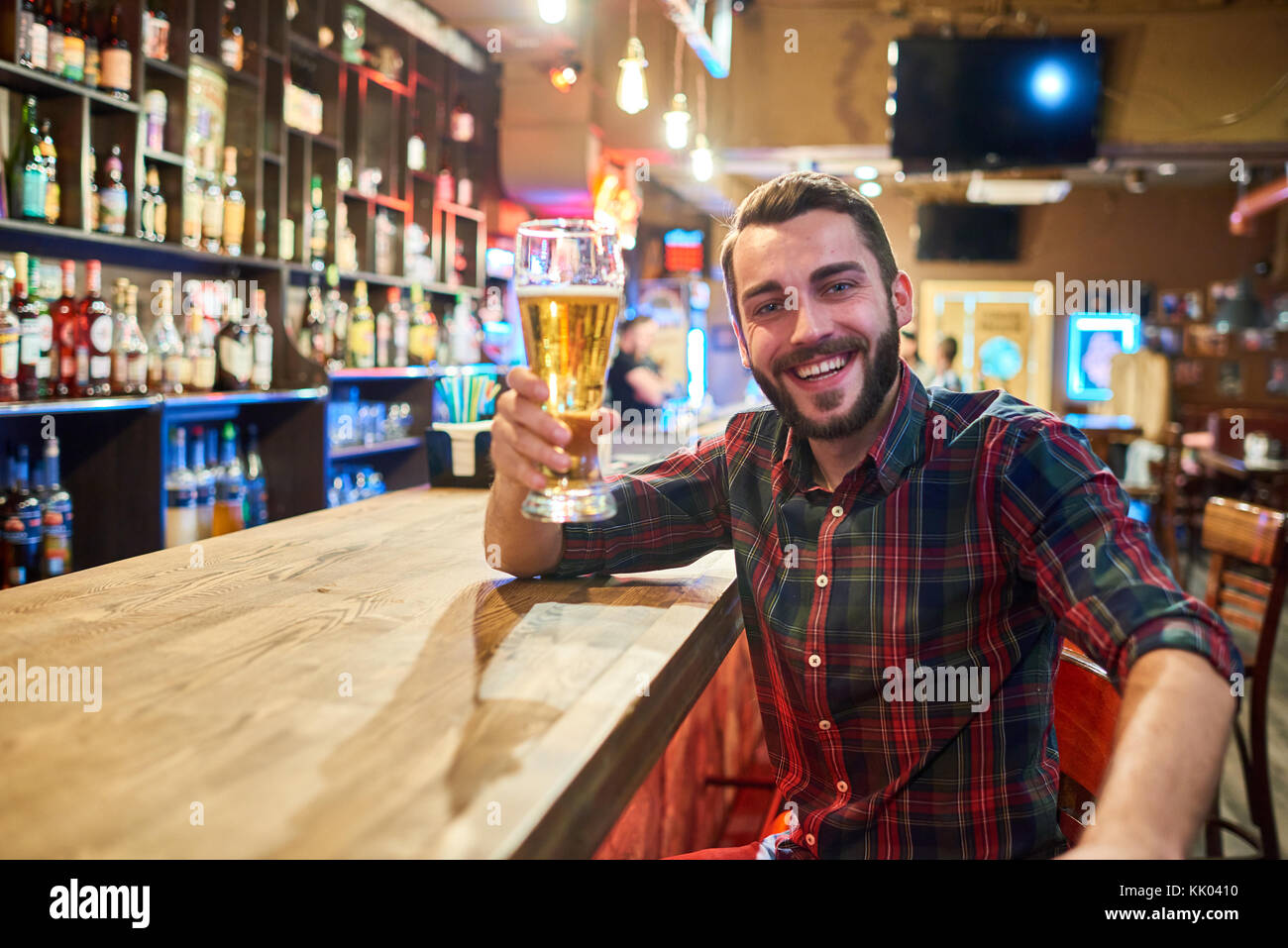 Ritratto di felice uomo barbuto tenendo alti bicchieri di birra tifo guardando la fotocamera mentre si divertono in pub, spazio di copia Foto Stock