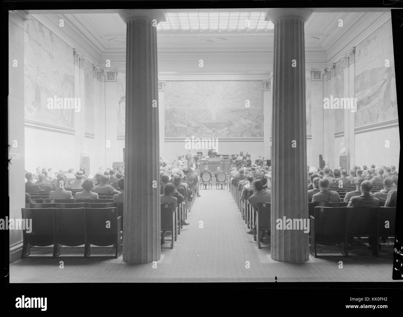 Questa foto cattura un momento storico in un auditorium universitario durante un concerto. Mostra l'interno dell'aula con un'orchestra che si esibisce per un pubblico. L'immagine riflette l'ambiente culturale e accademico del tempo. Foto Stock