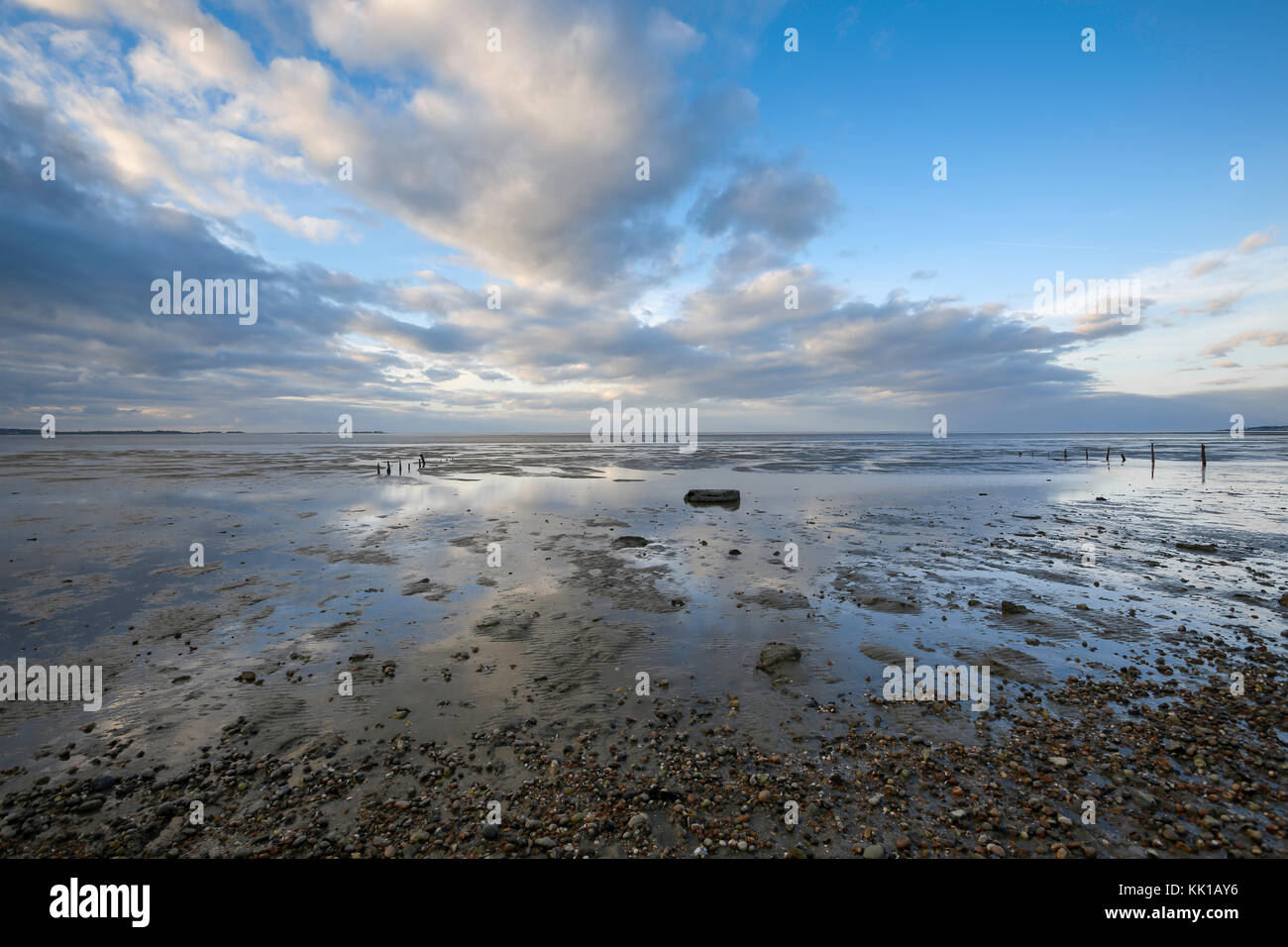 Interessante nuvole riflettono in pozze di acqua a bassa marea, Seasalter beach, whitstable kent, Regno Unito, guardando attraverso il Swale estuario. Foto Stock