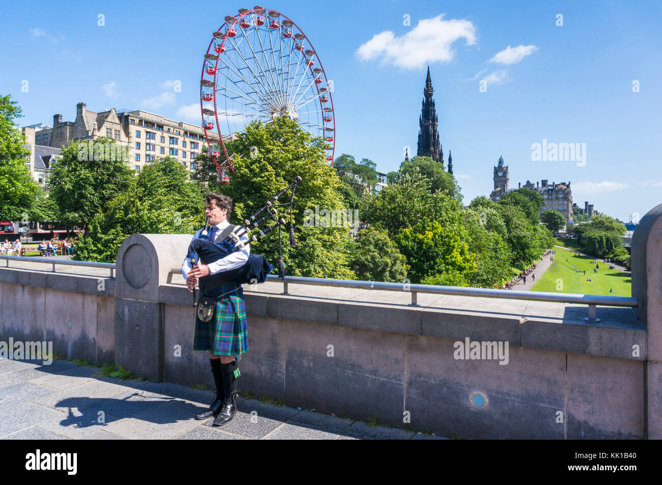 Edimburgo Scozia Edimburgo scottish piper giocando la cornamusa di fronte ai giardini di Princes street e la ruota di Edimburgo Edinburgh City Centre Regno Unito Foto Stock