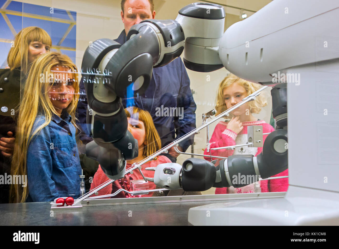 Bambini curiosi guardando la dimostrazione con robot industriale le armi in esposizione su robotica e intelligenza artificiale / ai Foto Stock