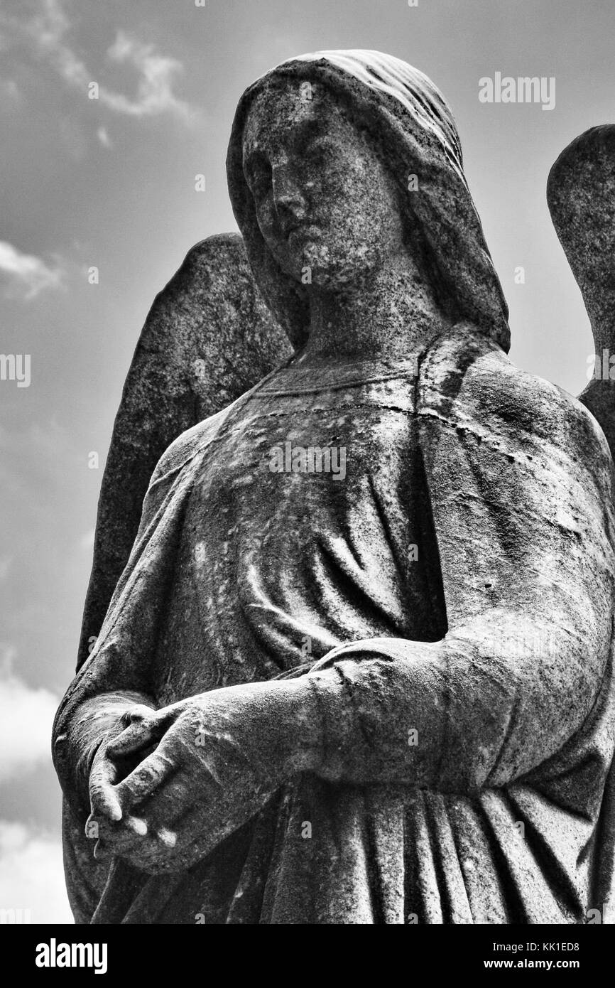 Un splendidamente scolpito angelo femmina si erge guarda sulla tomba di un fedele seguace. Foto Stock
