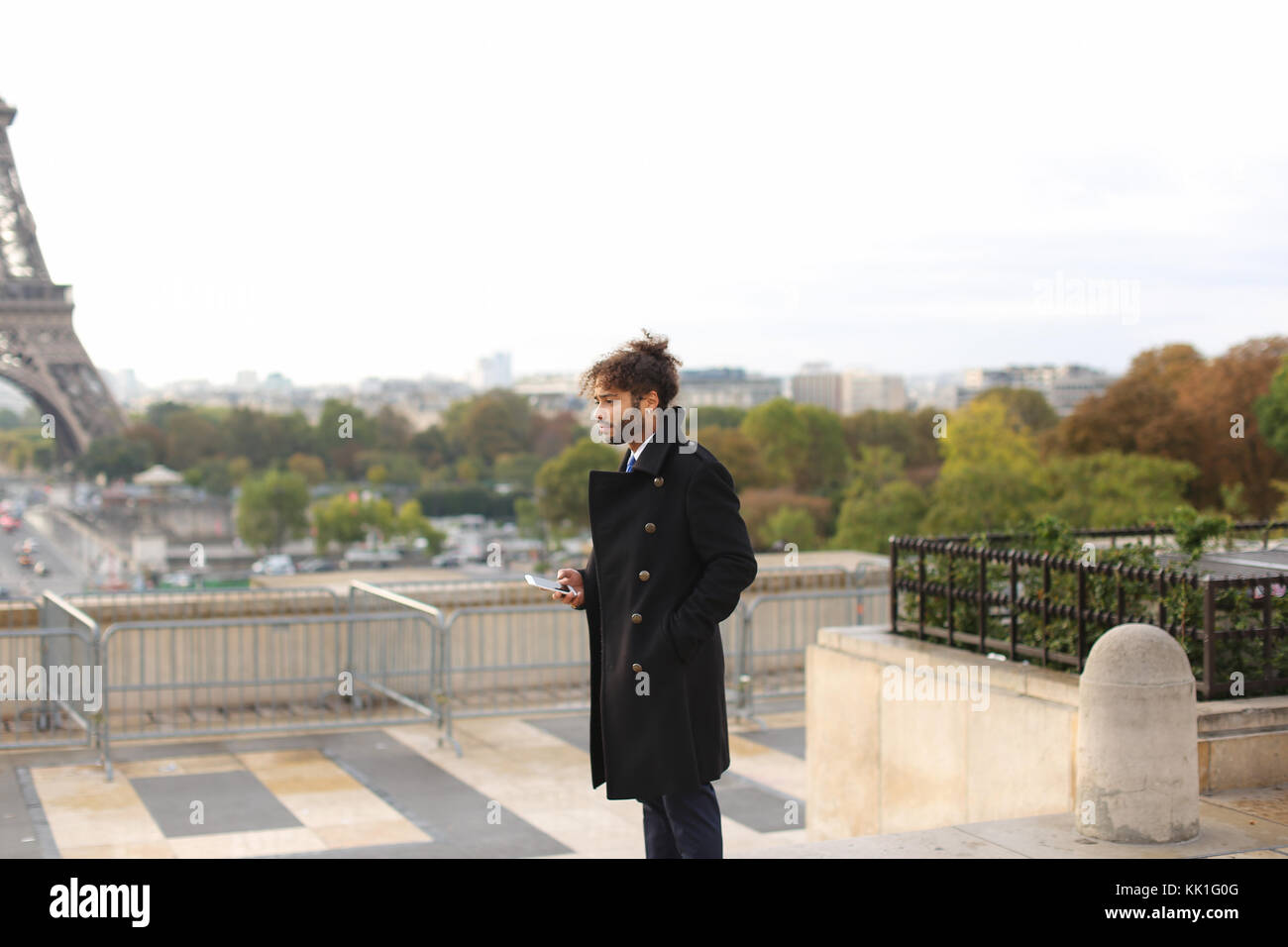 Arabian boy camminare vicino a torre eiffel con lo smartphone in slow mo Foto Stock