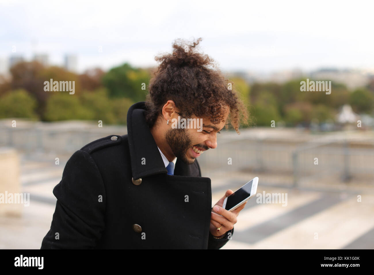 Arabian boy camminare vicino a torre eiffel con lo smartphone in slow mo Foto Stock